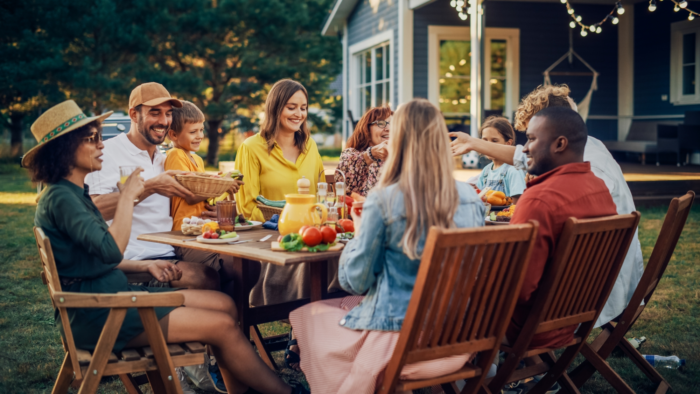 An image of a group of people sitting around an outdoor table, enjoying a meal